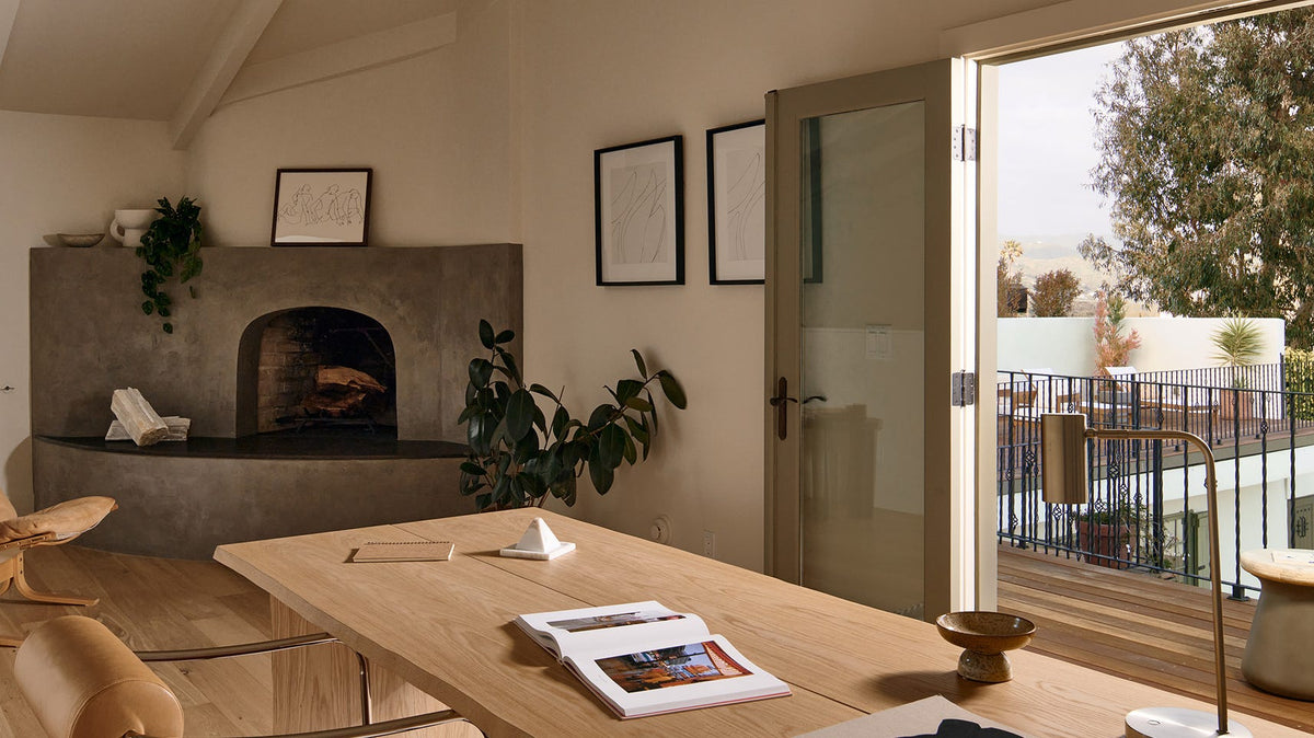 Despacho en casa con escritorio de madera maciza, chimenea de obra y salida a la terraza