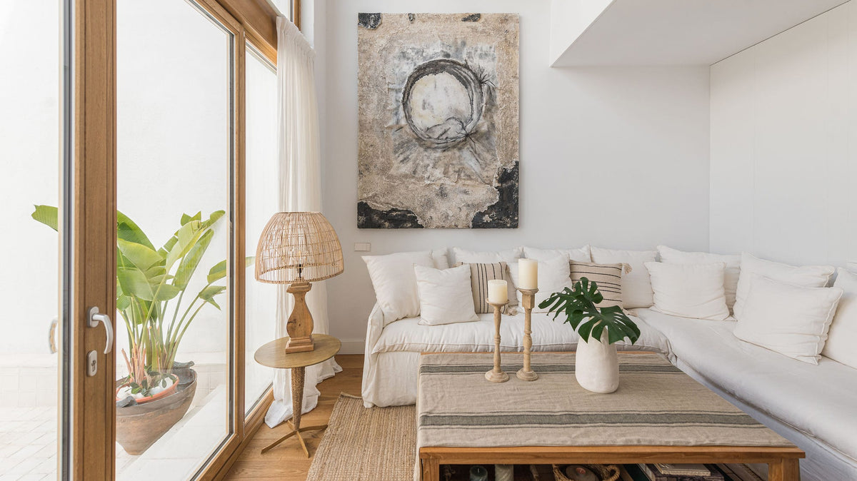 Salón mediterráneo con sofá rinconera de lino, mesa de centro de madera maciza, lámparas de yute y jarrones de cerámica