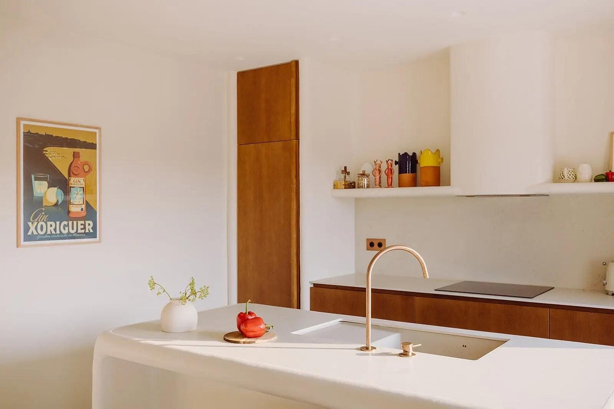 Cocina de estilo mediterráneo con isla central de madera y paredes blancas en una casa de Menorca