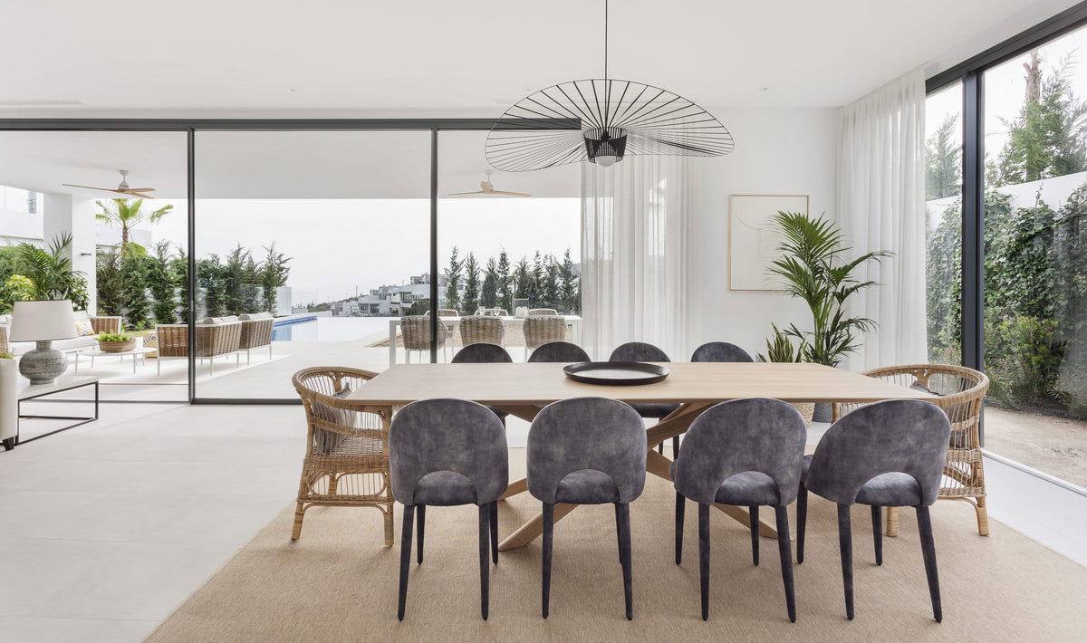 Comedor de estilo mediterráneo con mesa de madera abierto al porche en una casa de Marbella