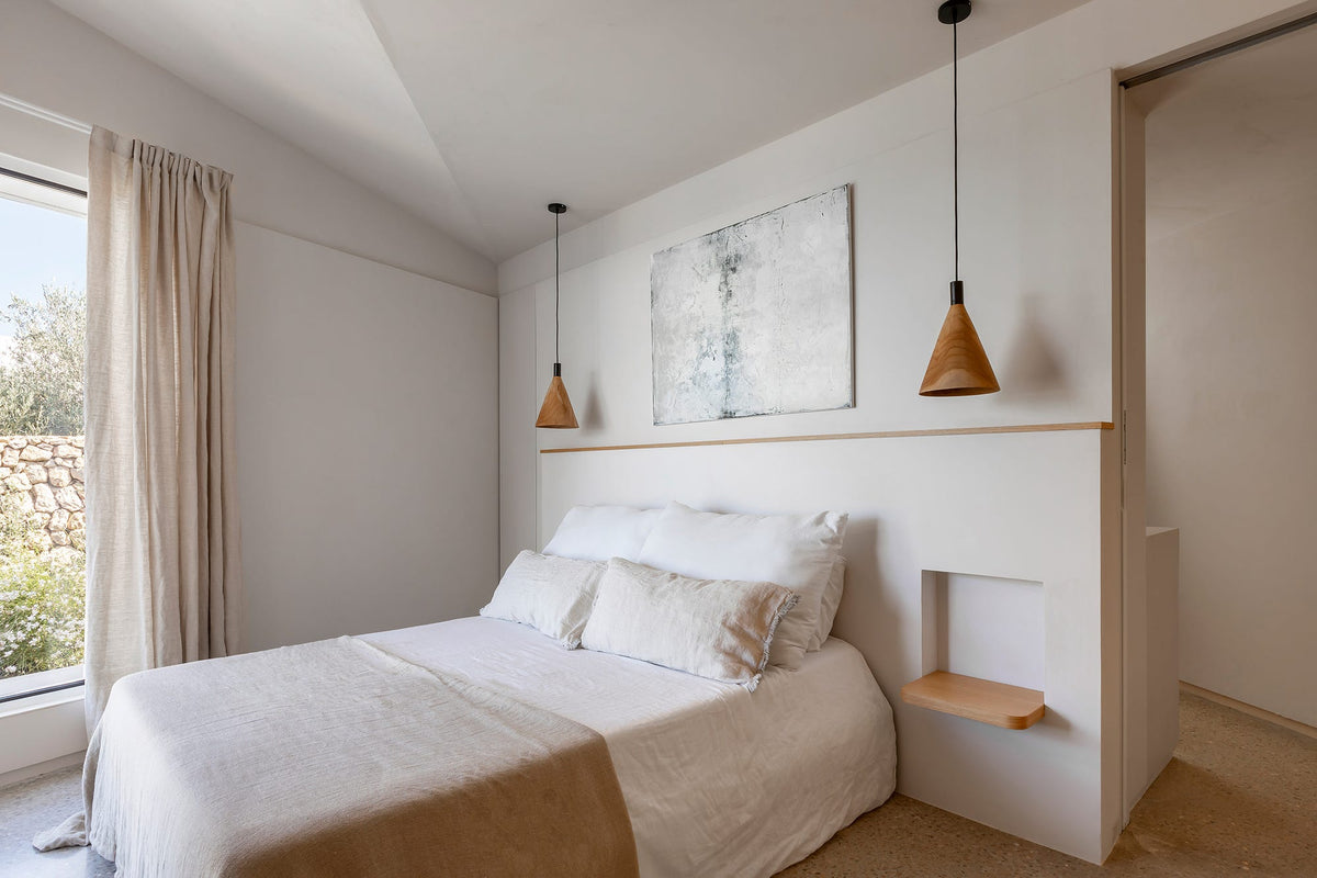 Dormitorio de estilo mediterráneo con cabecero de obra, paredes blancas y ropa de cama de lino