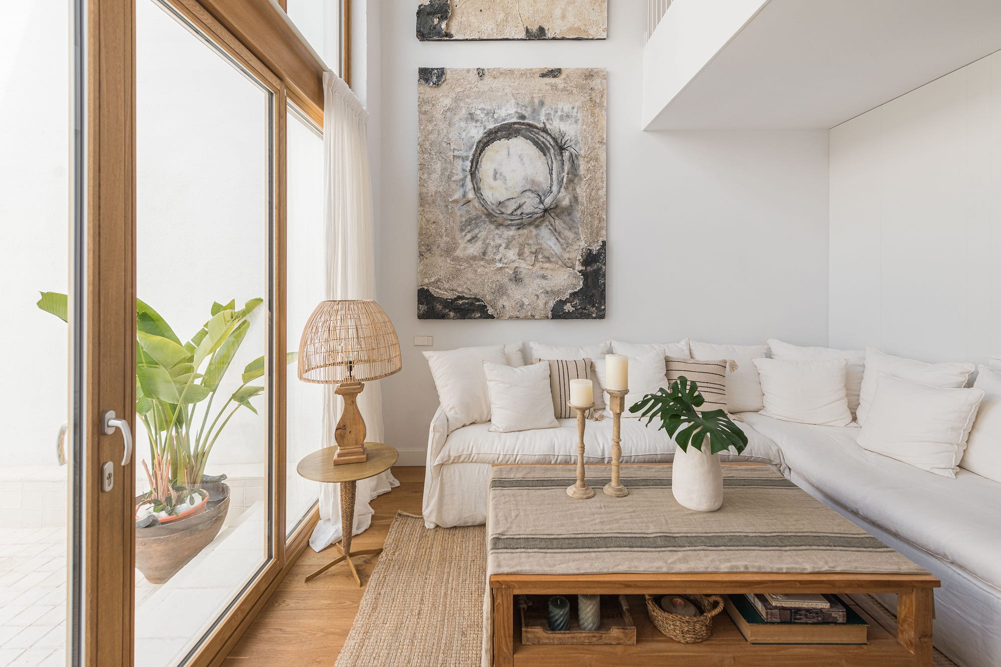 Salón mediterráneo con sofá rinconera de lino, mesa de centro de madera maciza, lámparas de yute y jarrones de cerámica