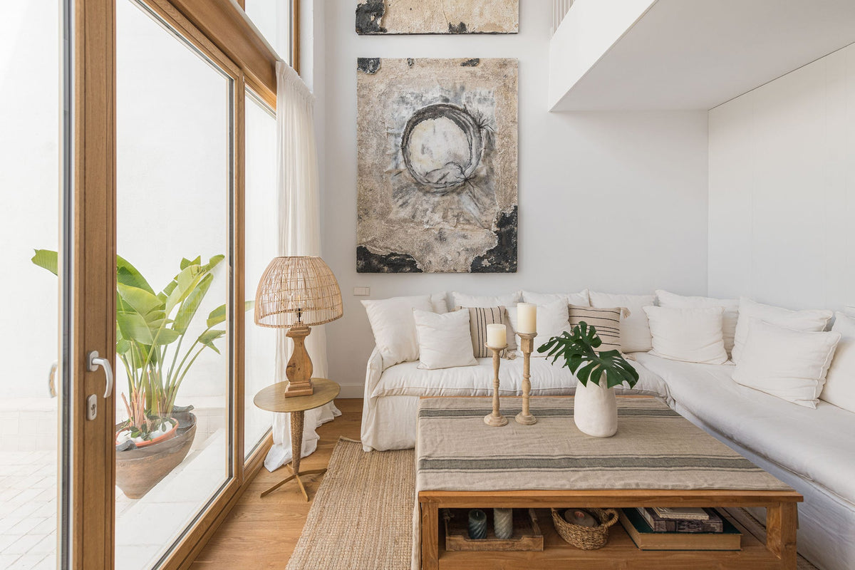 Salón mediterráneo con sofá rinconera de lino, mesa de centro de madera maciza, lámparas de yute y jarrones de cerámica