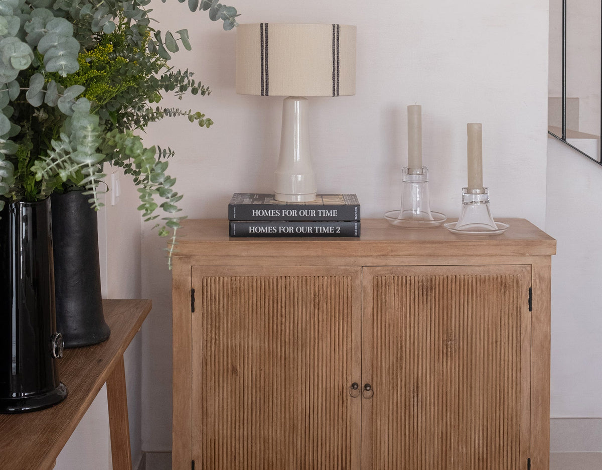 Aparador de madera con lámpara de mesa de cerámica y pantalla tejida en una casa de Sancti Petri