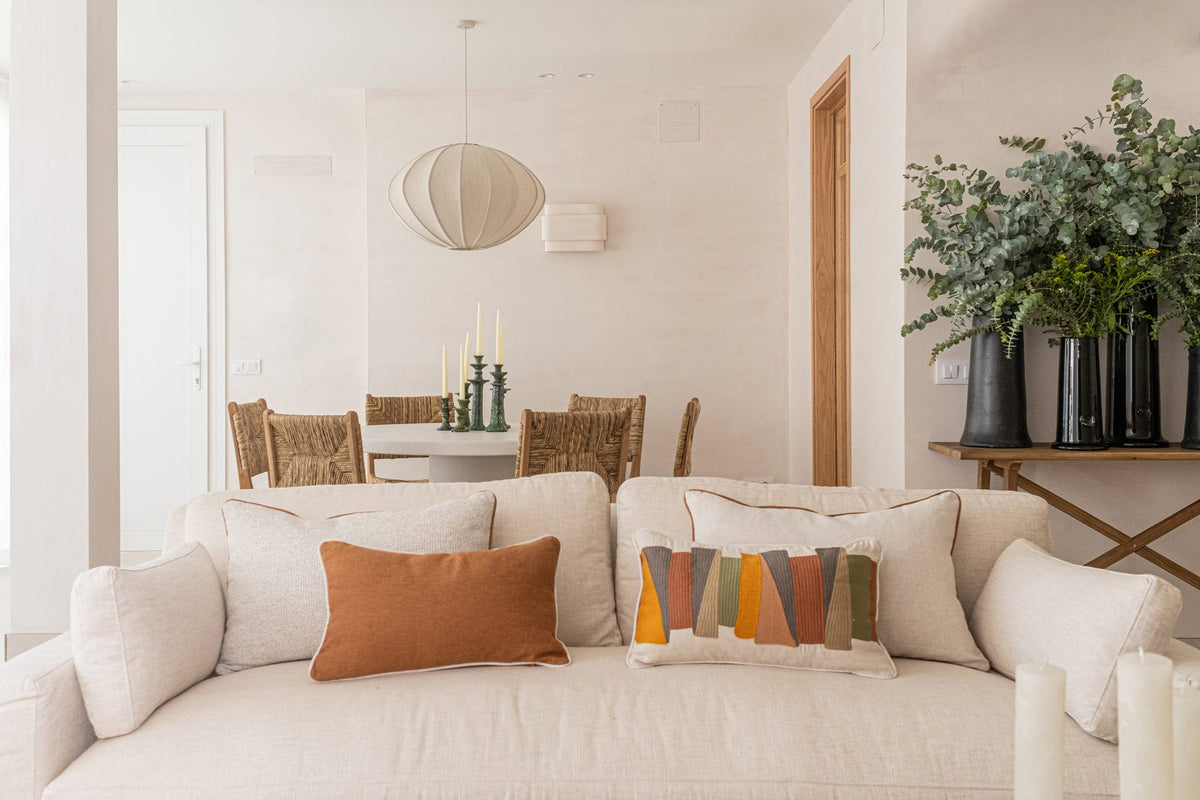 Salón de estilo mediterráneo con sofá de lino, cojines en tonos cálidos y mesa de centro de madera en una casa de Sancti Petri