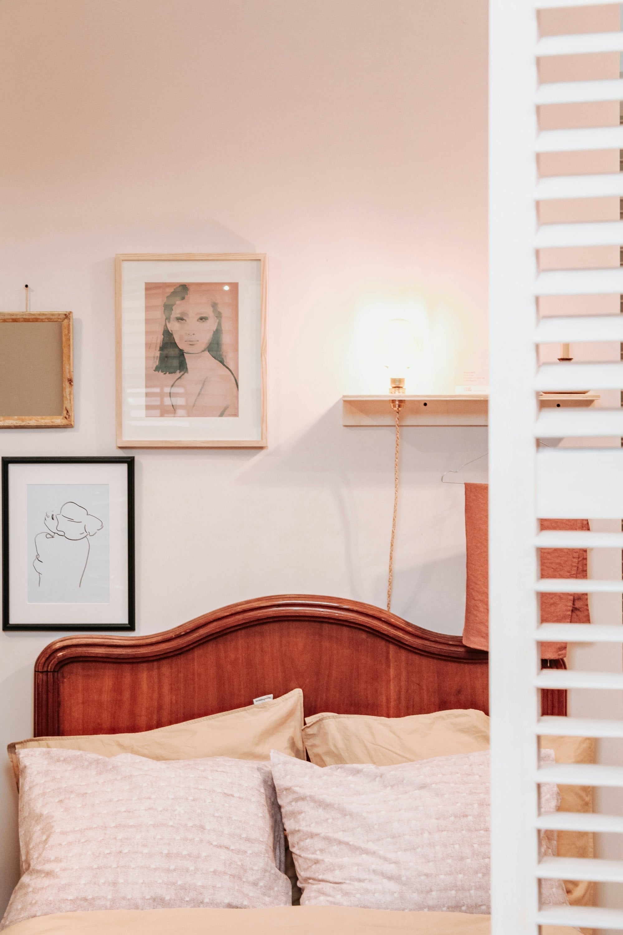 Dormitorio en tonos pastel con cuadros colgados sobre la cama