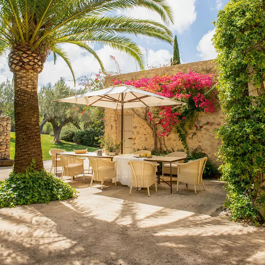 Comedor exterior mediterráneo con sillas de fibras naturales bajo una sombrilla - Pino & Jacaranda